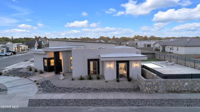 contemporary home with fence, a residential view, and stucco siding