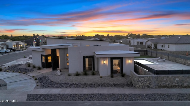 rear view of property featuring stucco siding, a residential view, and fence