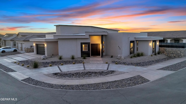modern home with an attached garage, stucco siding, and driveway