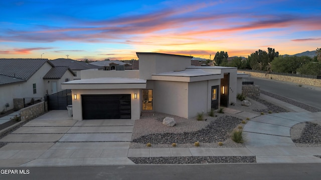 contemporary home with concrete driveway, fence, stucco siding, and a garage