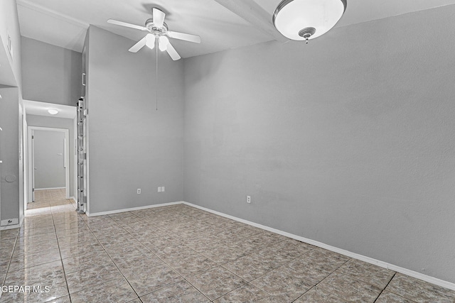 tiled empty room featuring ceiling fan and baseboards