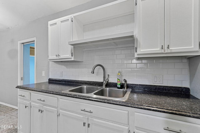 kitchen with white cabinetry, baseboards, decorative backsplash, and a sink