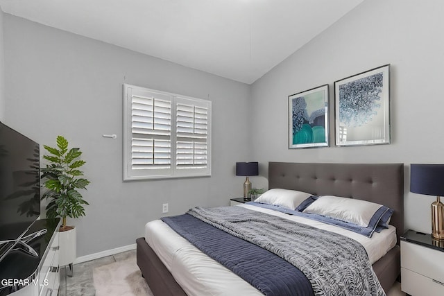 bedroom featuring lofted ceiling and baseboards