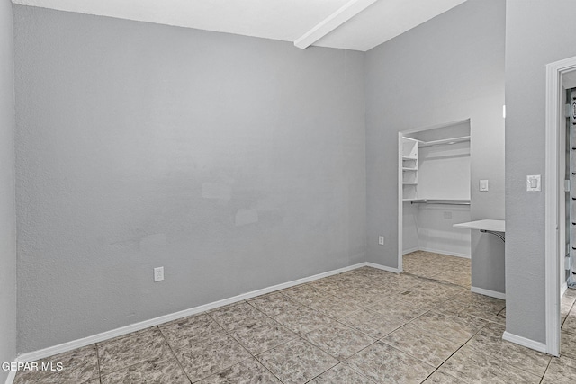 unfurnished bedroom featuring tile patterned floors, a spacious closet, a closet, and baseboards