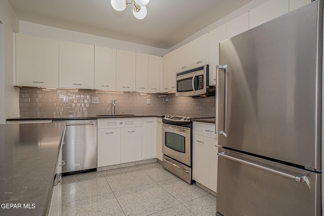 1800 N Stanton Unit 502, El Paso, TX 79902 - kitchen with dark countertops, a sink, backsplash, light speckled floor, and appliances with stainless steel finishes