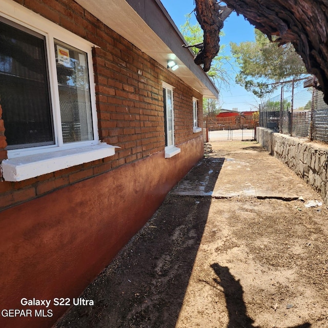 view of property exterior featuring brick siding and fence