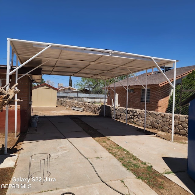 view of patio / terrace with fence, a storage unit, an outdoor structure, and an attached carport
