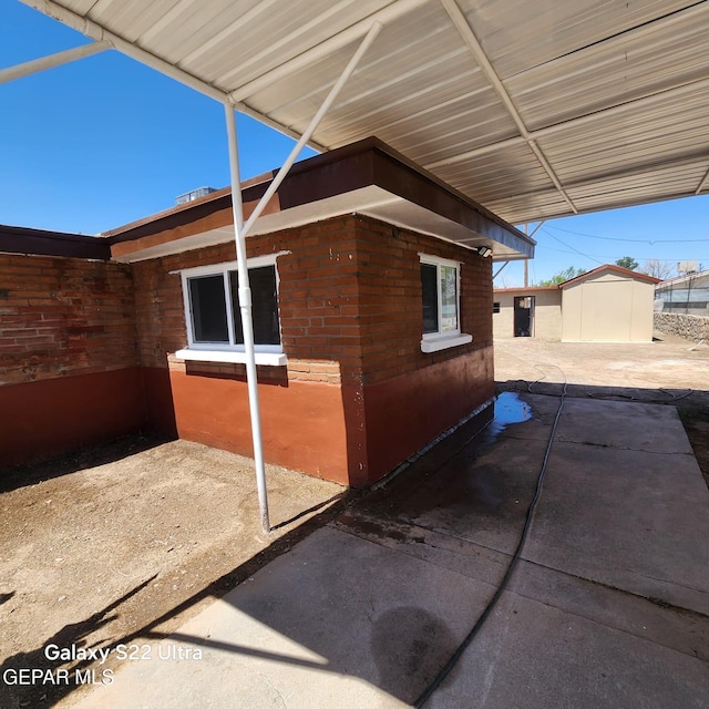 view of side of property featuring a storage unit, an outbuilding, and a patio