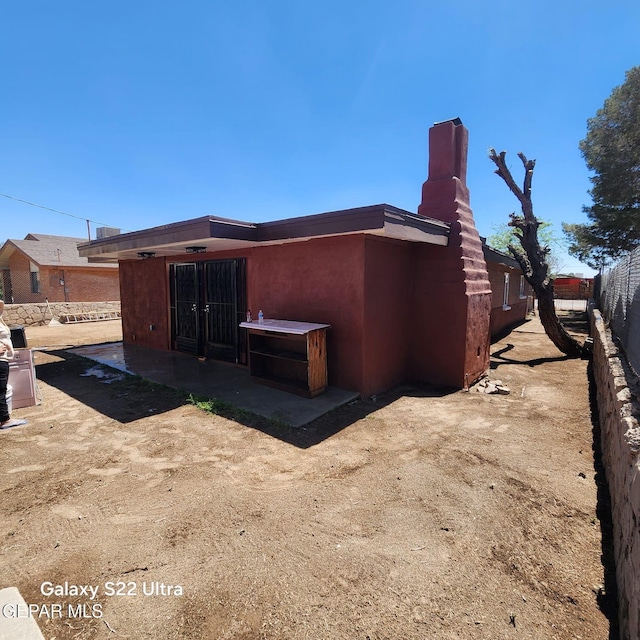 rear view of house with fence and a chimney