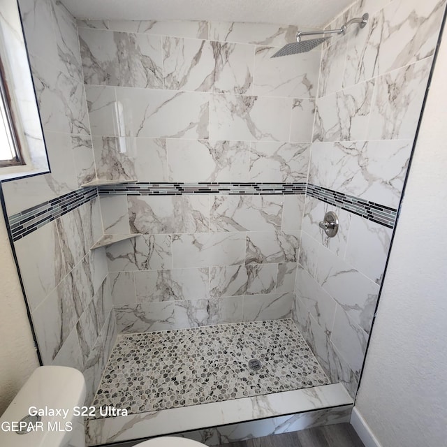bathroom featuring a tile shower and toilet
