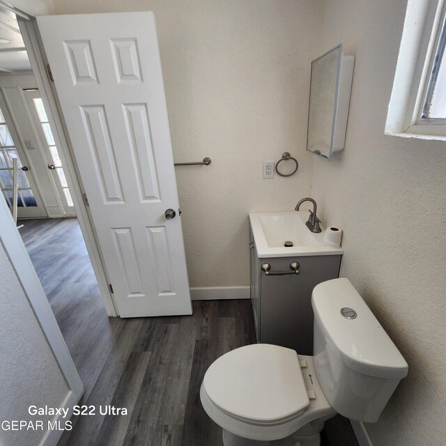bathroom featuring toilet, a healthy amount of sunlight, vanity, and wood finished floors