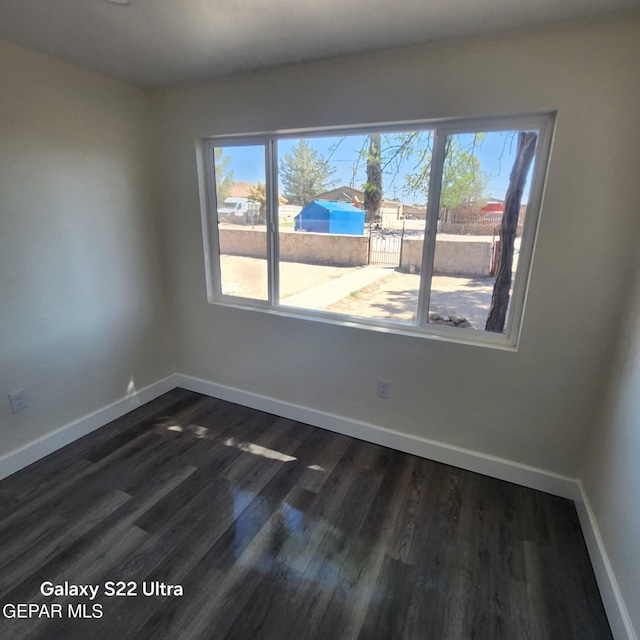 empty room with baseboards and dark wood-style floors