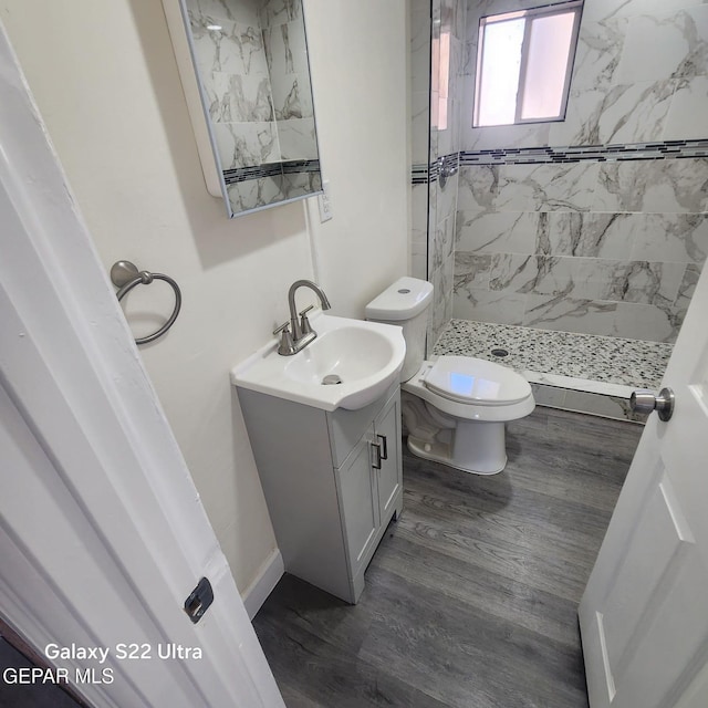 full bath featuring toilet, wood finished floors, vanity, and a stall shower