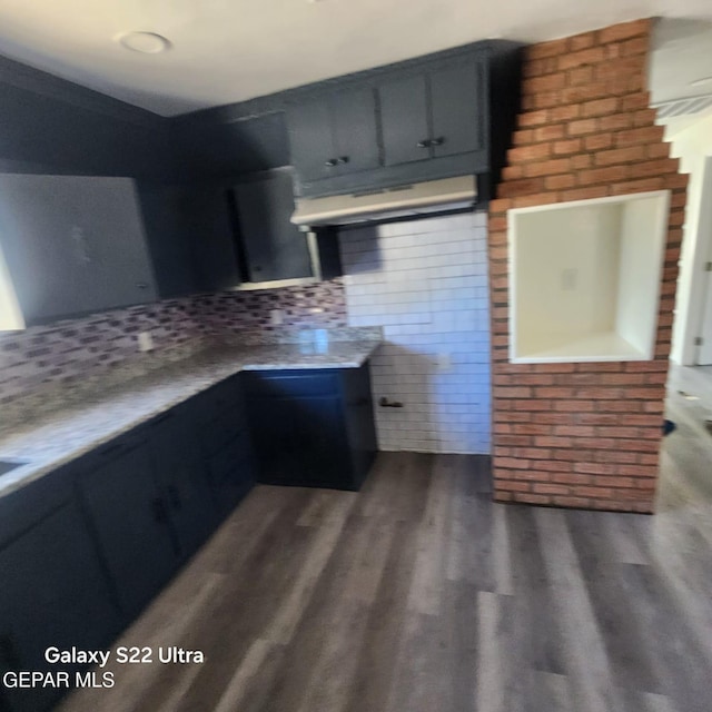 kitchen with light countertops, under cabinet range hood, wood finished floors, and decorative backsplash