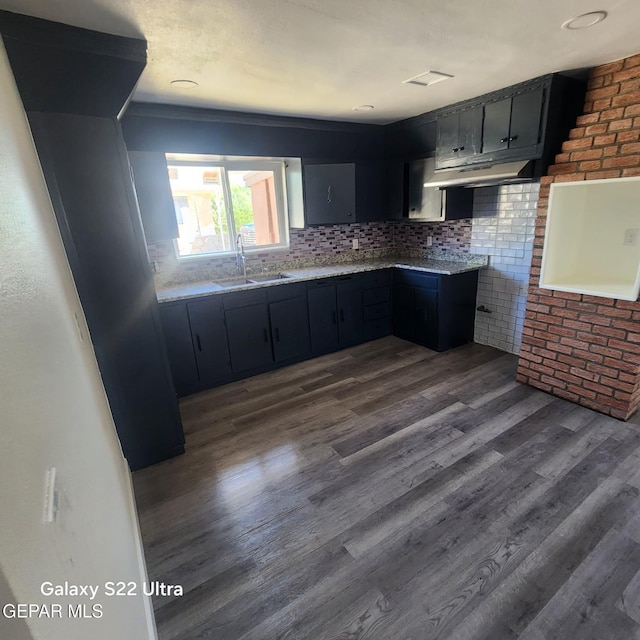 kitchen with tasteful backsplash, a sink, brick wall, dark wood finished floors, and visible vents