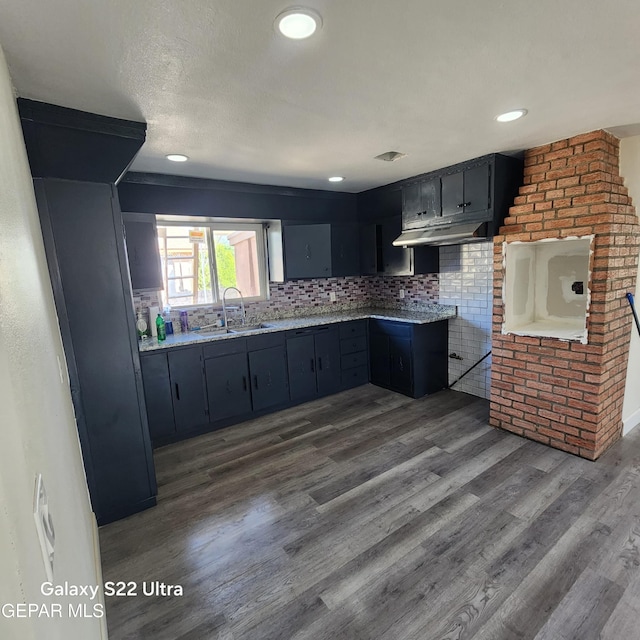 kitchen with tasteful backsplash, a sink, dark wood finished floors, under cabinet range hood, and recessed lighting