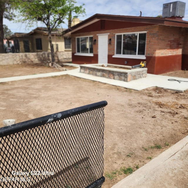 ranch-style house featuring a chimney, brick siding, and central AC unit
