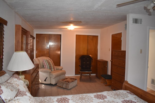 632 Mauer Rd, El Paso, TX 79915 - tiled bedroom featuring two closets and a textured ceiling