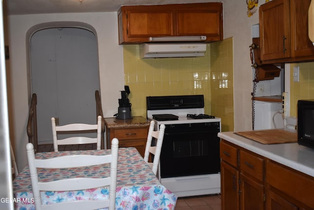 632 Mauer Rd, El Paso, TX 79915 - kitchen featuring white gas stove, extractor fan, brown cabinets, light countertops, and black microwave