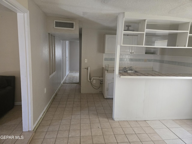 632 Mauer Rd, El Paso, TX 79915 - kitchen with light tile patterned floors, a textured ceiling, open shelves, light countertops, and backsplash