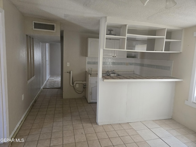 632 Mauer Rd, El Paso, TX 79915 - kitchen with a textured ceiling, backsplash, light tile patterned floors, open shelves, and light countertops