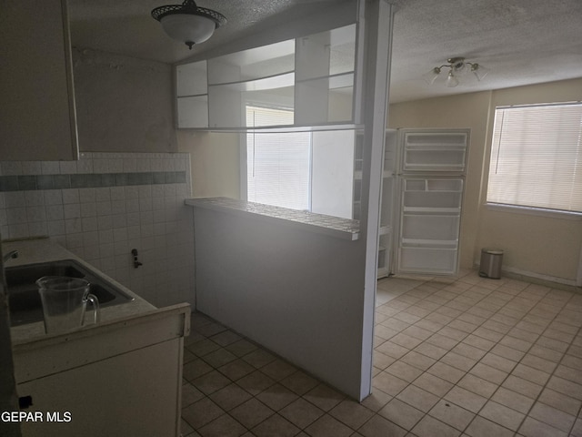 632 Mauer Rd, El Paso, TX 79915 - kitchen featuring tile patterned floors, tile walls, a textured ceiling, and light countertops