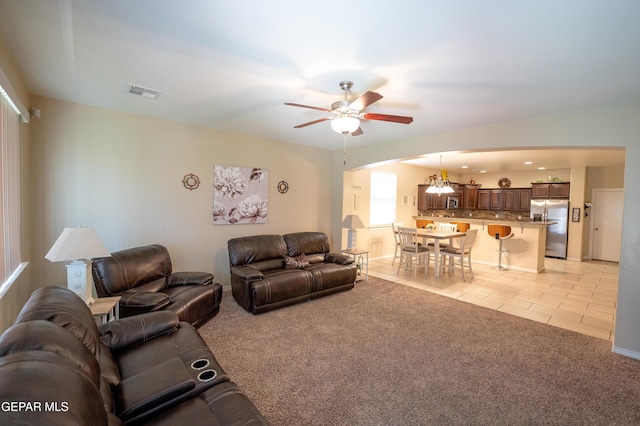 14700 Alton Oaks, El Paso, TX 79938 - living room with light tile patterned flooring, visible vents, ceiling fan with notable chandelier, arched walkways, and light colored carpet