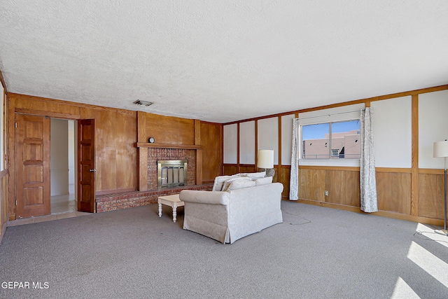 9668 Kathy Ave, El Paso, TX 79927 - living room featuring a textured ceiling, wooden walls, visible vents, carpet floors, and a brick fireplace