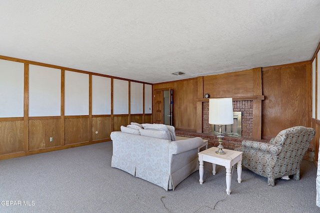 9668 Kathy Ave, El Paso, TX 79927 - carpeted living area with a fireplace, wooden walls, a textured ceiling, and visible vents