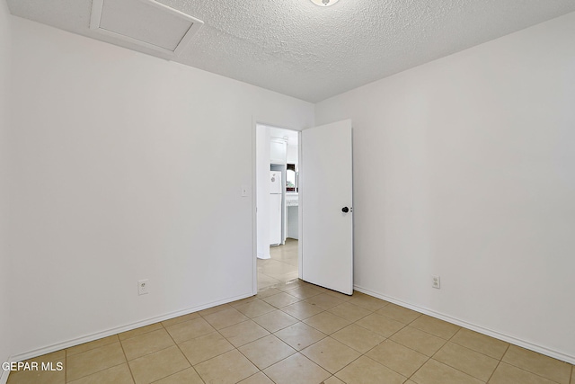 9668 Kathy Ave, El Paso, TX 79927 - spare room with attic access, a textured ceiling, baseboards, and light tile patterned flooring