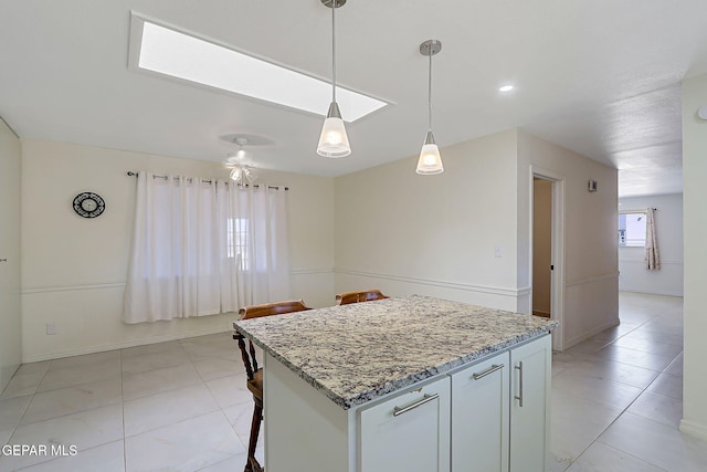 9668 Kathy Ave, El Paso, TX 79927 - kitchen featuring light stone counters, a breakfast bar area, light tile patterned floors, pendant lighting, and a kitchen island