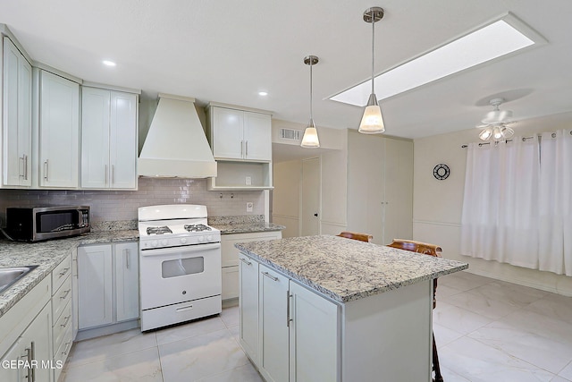9668 Kathy Ave, El Paso, TX 79927 - kitchen with white range with gas cooktop, marble finish floor, stainless steel microwave, and custom range hood