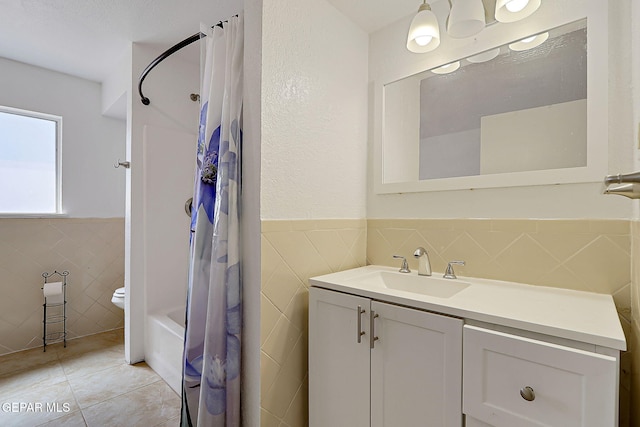 9668 Kathy Ave, El Paso, TX 79927 - bathroom featuring tile patterned flooring, toilet, vanity, tile walls, and wainscoting