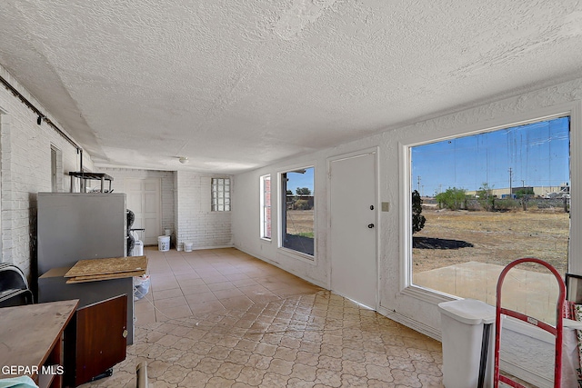 9668 Kathy Ave, El Paso, TX 79927 - interior space featuring brick wall and a textured ceiling