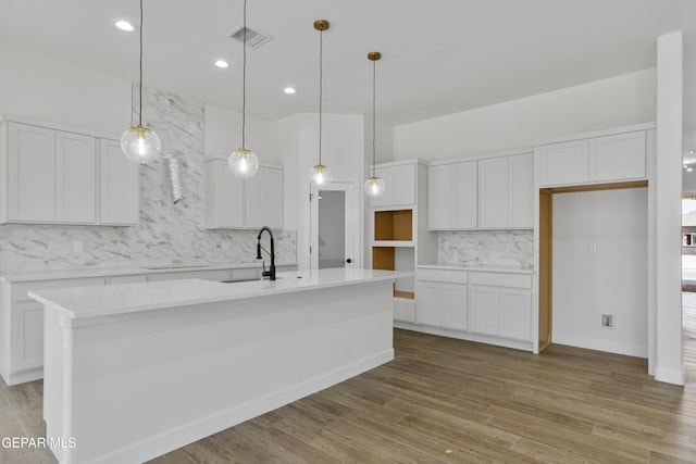3780 Surmise St, El Paso, TX 79938 - kitchen featuring a sink, tasteful backsplash, white cabinets, cooktop, and an island with sink