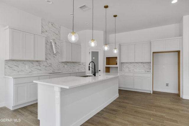 3780 Surmise St, El Paso, TX 79938 - kitchen with a sink, decorative backsplash, a kitchen island with sink, wood finished floors, and white cabinetry