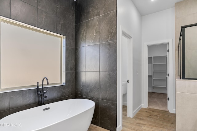 3749 Focus Pl, El Paso, TX 79938 - full bathroom featuring wood finished floors, a soaking tub, a spacious closet, tile walls, and baseboards