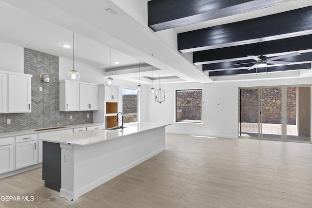 kitchen with decorative backsplash, a ceiling fan, light countertops, open floor plan, and white cabinetry