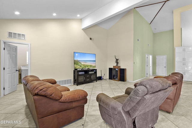 living area with high vaulted ceiling, washer / clothes dryer, visible vents, and light tile patterned floors