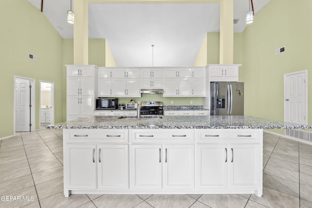 kitchen with high vaulted ceiling, under cabinet range hood, appliances with stainless steel finishes, and white cabinets