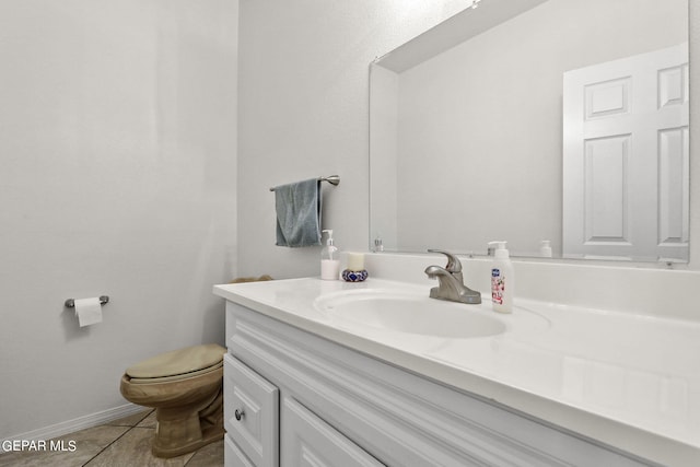 half bathroom featuring tile patterned flooring, baseboards, toilet, and vanity