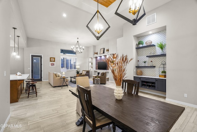dining area featuring visible vents, light wood-style flooring, baseboards, and an inviting chandelier