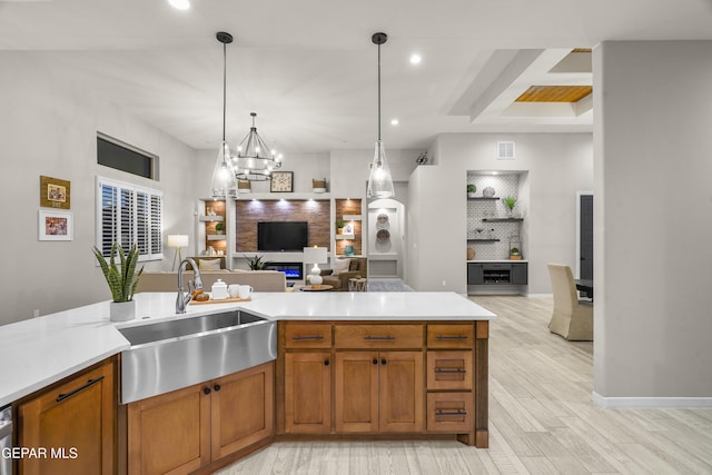 kitchen with a sink, light wood-style floors, light countertops, brown cabinetry, and open floor plan