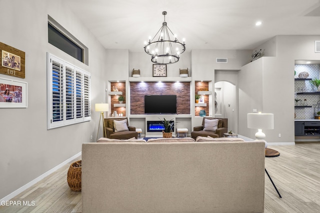 living room featuring visible vents, arched walkways, light wood finished floors, and baseboards