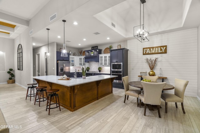 kitchen featuring visible vents, appliances with stainless steel finishes, light wood-type flooring, light countertops, and custom exhaust hood
