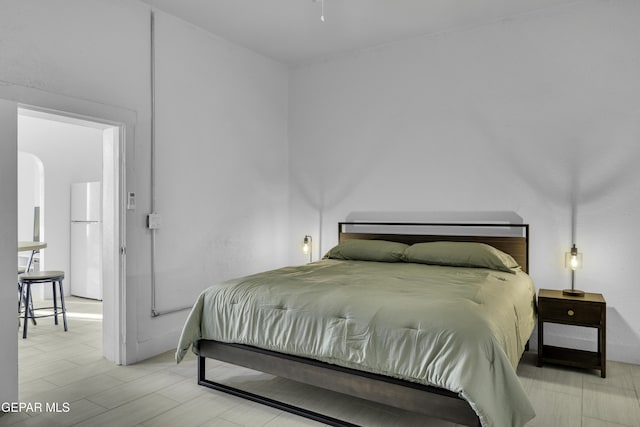 bedroom with arched walkways and freestanding refrigerator