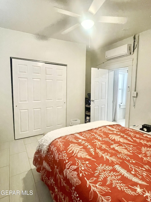 bedroom with an AC wall unit, tile patterned flooring, ceiling fan, and a closet