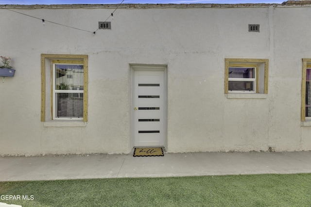 entrance to property featuring stucco siding