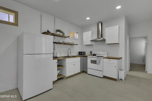 kitchen featuring a sink, white appliances, wall chimney range hood, open shelves, and butcher block counters
