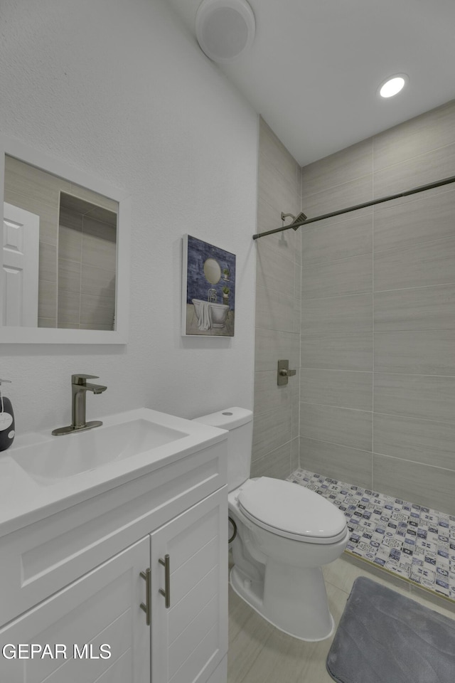 full bathroom featuring vanity, toilet, and tiled shower